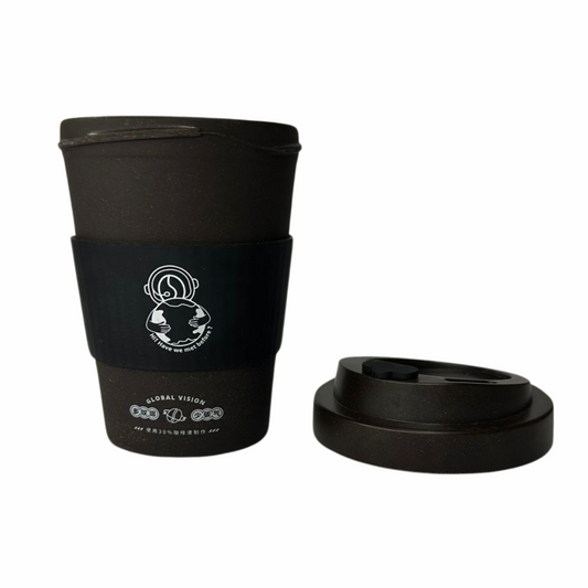 Copo preto com tampa removível ao lado, destacando sua luva de silicone preta com design estilizado de uma figura segurando o planeta e a frase "Haven't we met before?".