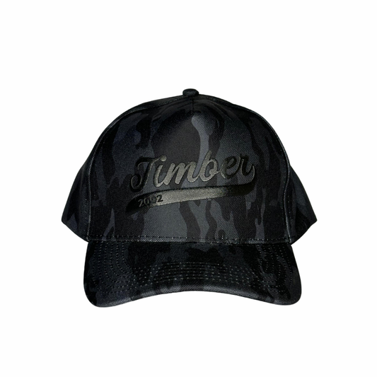 Logo "Timber" em preto brilhante no centro, com inscrição "2002" discreta abaixo.
