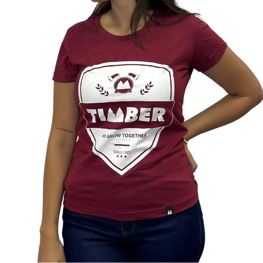 Modelo usando camiseta vermelha feminina 100% algodão com estampa branca 'TIMBER' e slogan 'We Grow Together'.