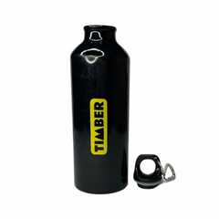 Garrafa preta com acabamento brilhante, formato cilíndrico e design minimalista. A tampa possui alça de metal para facilitar o transporte. O logotipo "Timber" em amarelo está destacado verticalmente na lateral.
