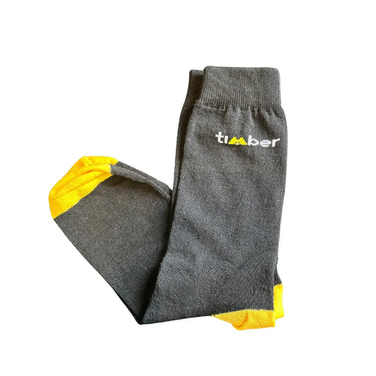 Meia de cano médio na cor preta, trazendo um estilo clássico e versátil. Detalhes em amarelo vibrante na ponta dos pés e no calcanhar, adicionando um toque moderno. Logo "Timber" bordado na lateral, reforçando a identidade da marca. Confortável e resistente, ideal para o dia a dia e aventuras ao ar livre.