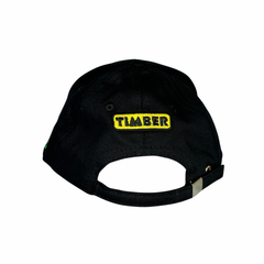 Vista traseira do boné preto com o texto "TIMBER" bordado em amarelo e preto no centro.