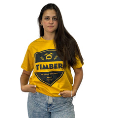 Modelo usando camiseta amarela feminina 100% algodão com estampa preta 'TIMBER' e slogan 'We Grow Together'.